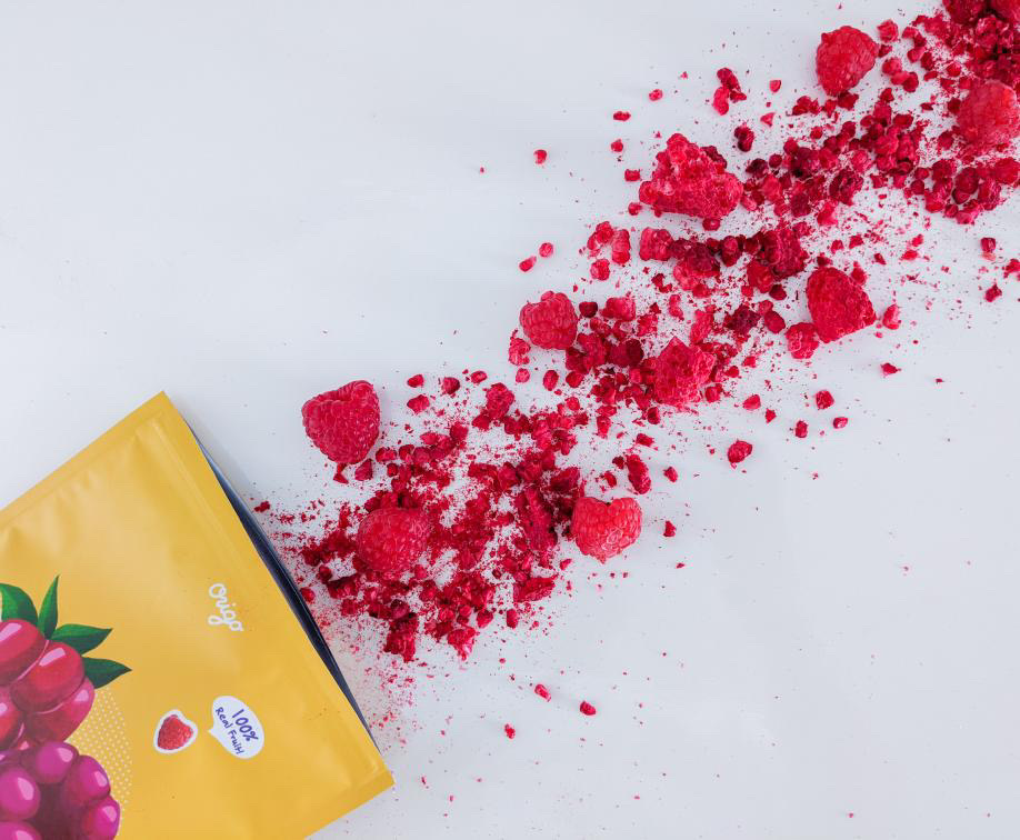 Origo freeze-dried raspberries scattered beside a yellow raspberry pouch