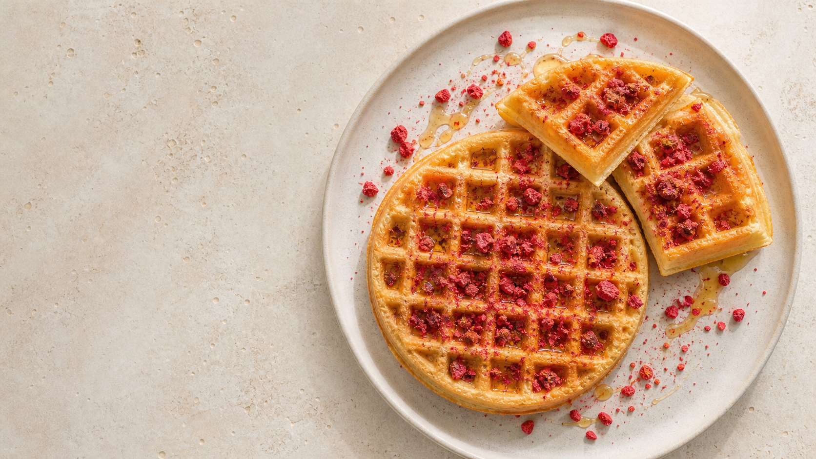 Waffles topped with crushed Origo freeze-dried raspberry and honey