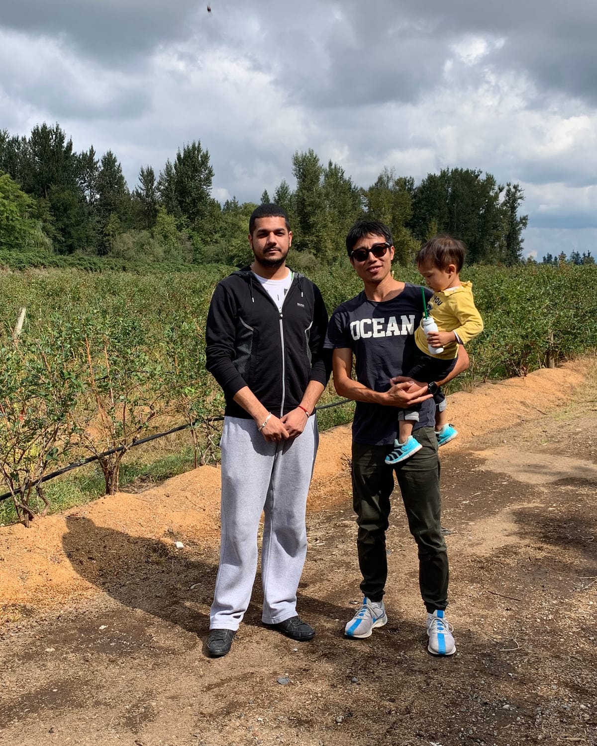 A fruit grower standing with Origo founder Stone and his young son at the farm